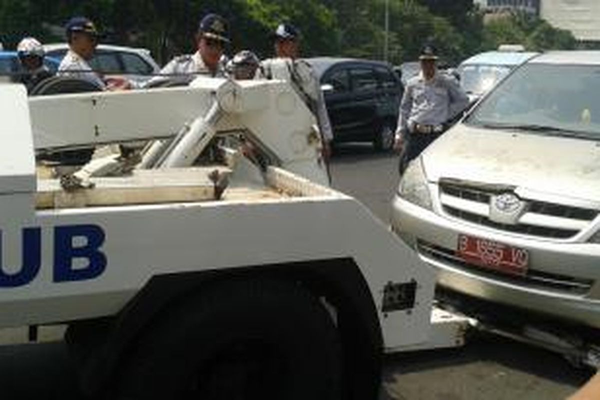 Sebuah mobil Toyota Innova berpelat merah diderek petugas dari Dinas Perhubungan dalam penertiban parkir liar di Jalan Gajah Mada, tepatnya di depan PN Jakarta Pusat, Selasa (9/9/2014).