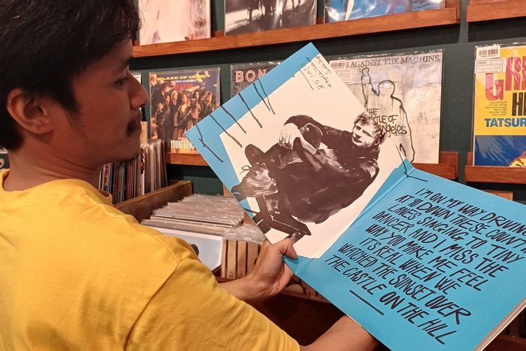 Salah satu staf toko kaset 33RPM bernama Bram (27) saat menunjukkan vinyl yang diberikan Ed Sheeran secara gratis ke tokonya yang terletak di Pasar Santa, Jakarta Selatan, Minggu (3/3/2024).
