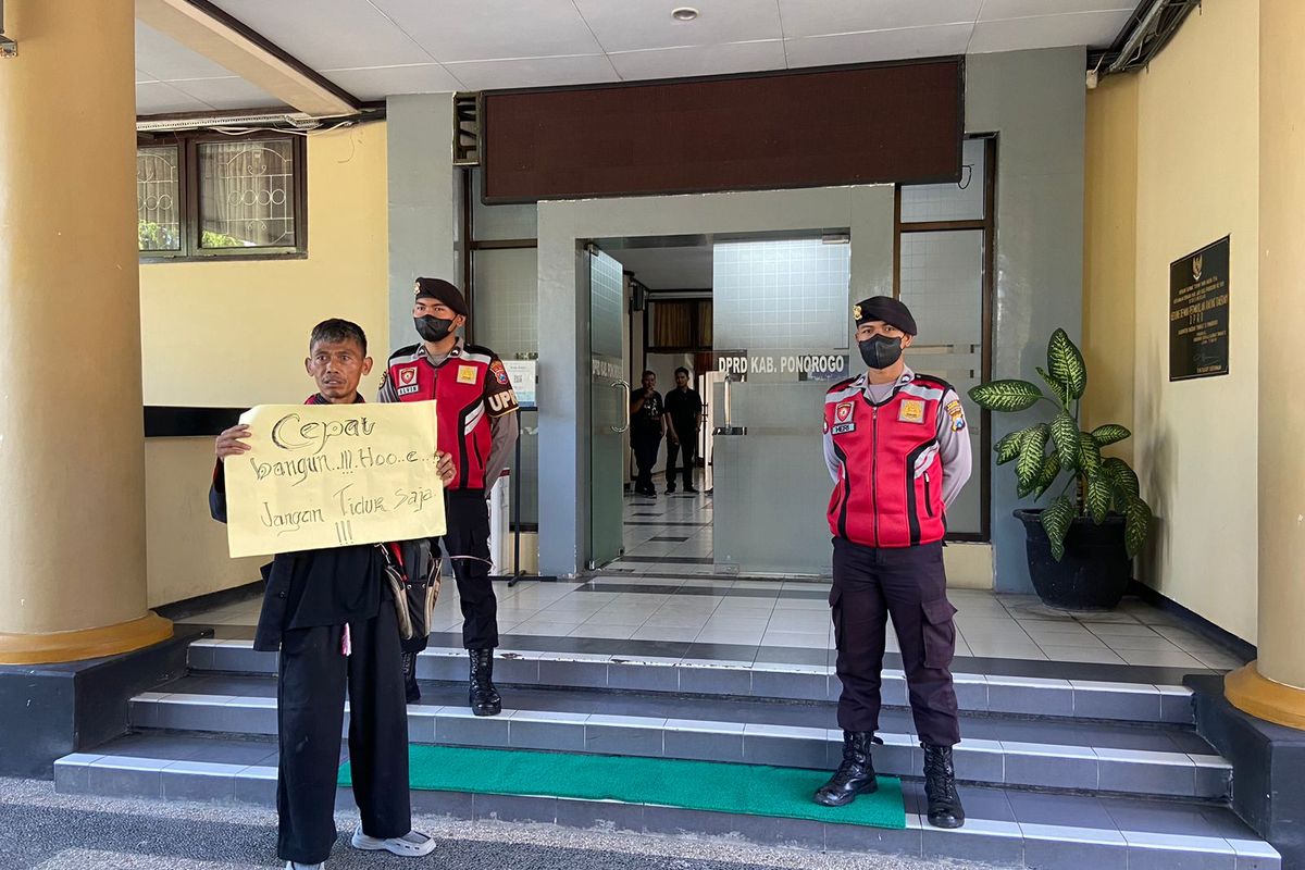 UNJUK RASA TUNGGAL-Memperingati  hari anti korupsi, seorang pria nekat menggelar aksi unjuk rasa tunggal di Kejaksaan Negeri Kabupaten Ponorogo, Jumat (9/12/2022). Tak hanya itu, pria bernama Pujiana juga menggelar aksi serupa di DPRD dan Kantor Pemkab Ponorogo