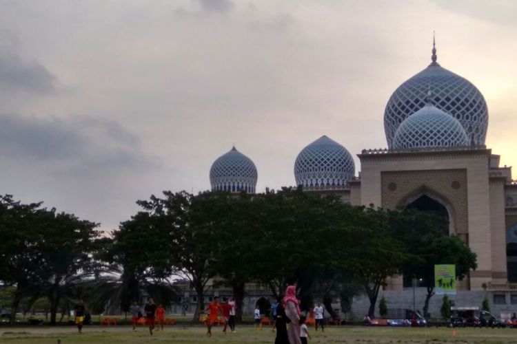 Warga berjalan diantara kabut asap di Lapangan Hiraq, Kota Lhokseumawe, Aceh, Sabtu (22/7/2017) 