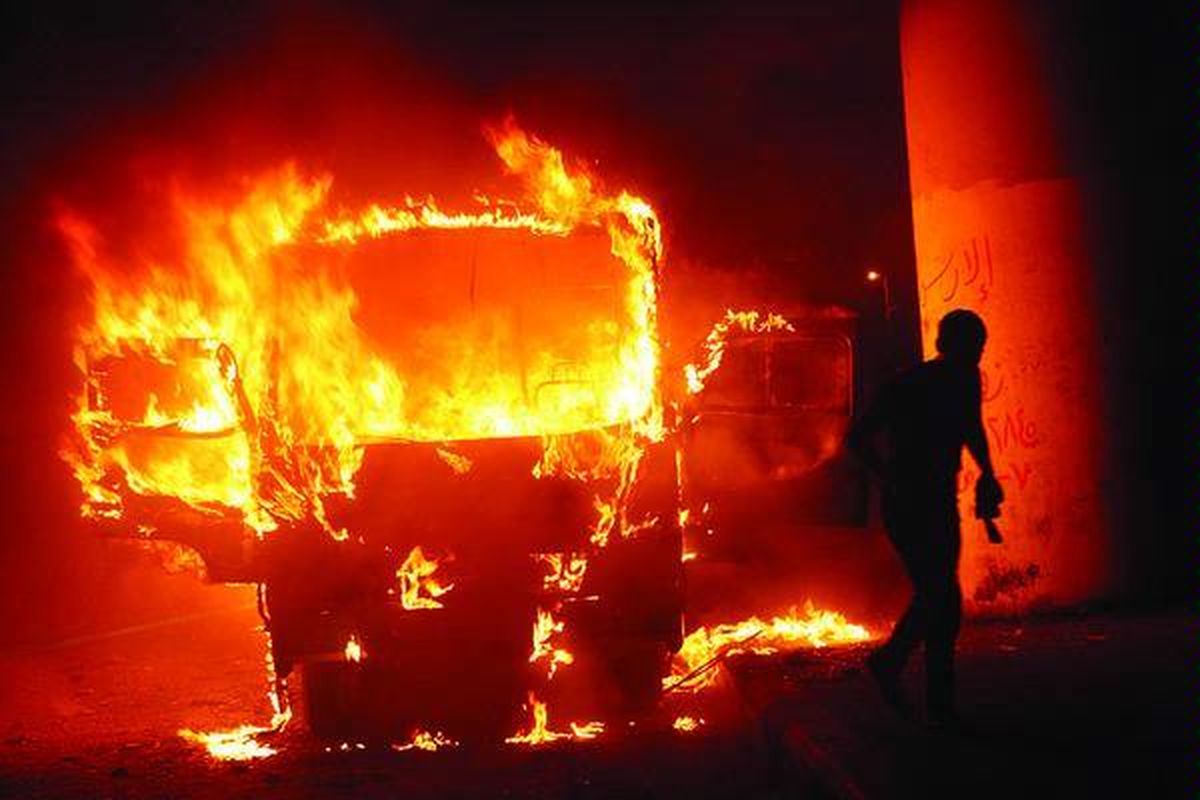 Seorang warga Kairo melintas di depan sebuah bus yang dibakar saat pecah bentrokan antara para pendukung dan penentang Presiden Mesir Muhammad Mursi di Alun-alun Tahrir, Kairo, Jumat (12/10). Bentrokan pecah sehari setelah Mursi berusaha memberhentikan Jaksa Agung Mesir Abdel Meguid Mahmud dengan cara mengangkatnya sebagai duta besar. Keputusan Mursi itu akhirnya dicabut.