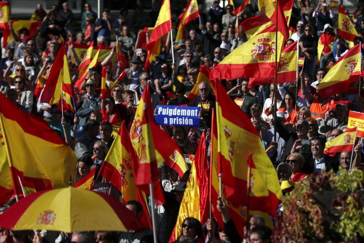 Demonstran pro-persatuan berkumpul membawa spanduk meminta penangkapan Presiden Catalonia yang dipecat Carles Puigdemont di Madrid, Spanyol, Sabtu (28/10).