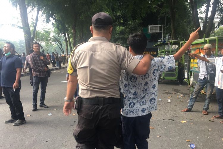 Salah satu siswa yang diamankan petugas saat aksi di depan gedung DPRD Sumut, Jumat sore (27/9/2019). Mereka menggunakan cara khusus untuk bersembunyi dari kejaran polisi. Mereka berpura-pura menjumpai seseorang di warung dan seolah-olah anak dari seorang pria paruh baya.