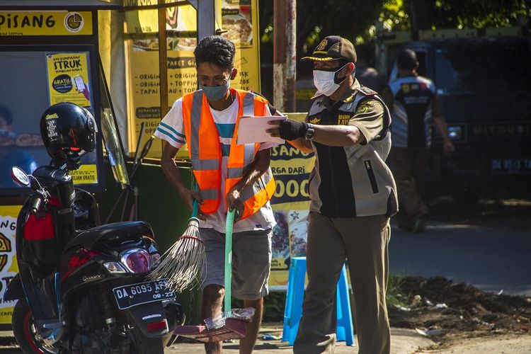 Anggota Satpol PP memberikan sanksi sosial kepada warga yang melanggar protokol kesehatan saat razia yustisi penegakan protokol kesehatan (Prokes) COVID-19 di Banjarmasin, Kalimantan Selatan, Selasa (10/8/2021). Berdasarkan data monitoring kepatuhan protokol kesehatan milik satgas COVID-19 setempat kepatuhan penggunaan masker turun menjadi 86 persen dari semula 94 persen meski kota Banjarmasin resmi memperpanjang PPKM level 4 dari 10 Agustus hingga 23 Agustus 2021. ANTARA FOTO/Bayu Pratama S/aww.   