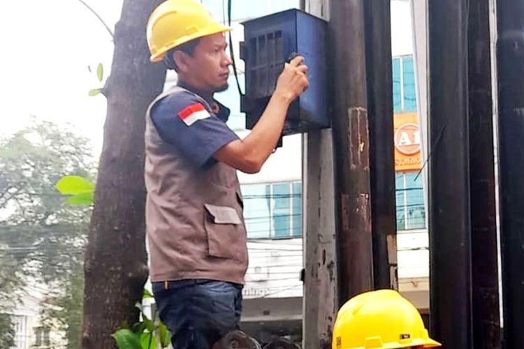 Petugas PLN saat mencabut meteran listrik (KWH Meter) pedagang martabak di Jalan Gajah, Kota Medan bernama, Amen, Rabu (15/5/2024). Pencabutan dilakukan karena Amen berjualan menggunakan mobil diatas trotoar