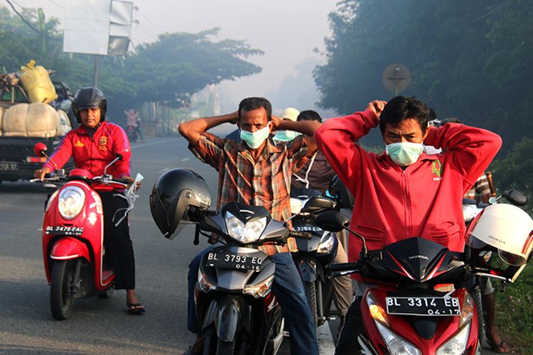 Penggunakan roda dua sedang memakai masker yang dibagikan oleh Komutnitas Peduli Keselamatan Bersama (KPKB) di Jalan Meulaboh - Banda Aceh, Kawasan Desa Suak Raya, Kecamatan Johan Pahlawan, Kabupaten Aceh Barat,  Sabtu (22/07/17)