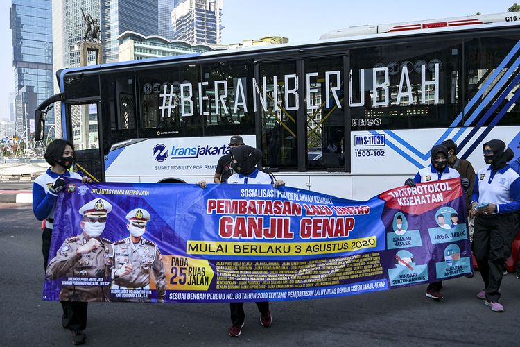 Sejumlah anggota Kepolisian membentangkan spanduk sosialisasi pemberlakuan kembali ganjil genap di Bundaran Hotel Indonesia, Jakarta, Minggu (2/8/2020). Pemprov DKI Jakarta menerapkan kembali aturan ganjil genap bagi kendaraan roda empat saat masa Pembatasan Sosial Berskala Besar (PSBB) transisi mulai Senin (3/8/2020) di 25 ruas jalan Ibu Kota.