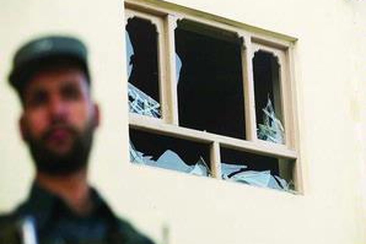 Seorang polisi Afganistan berdiri dan berjaga di samping jendela pecah di sebuah tempat tinggal, setelah beberapa roket menghunjam Kabul, dekat kedutaan AS, Selasa (4/8). Sedikitnya ada lima roket bom dilontarkan kelompok Taliban ke Kabul pada Selasa dini hari.