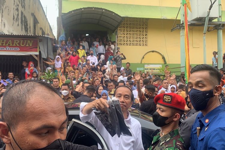 Presiden Jokowi membagikan baju kaos kepada warga di Pasar Bawah di Kota Pekanbaru, Riau, Rabu (4/1/2023).