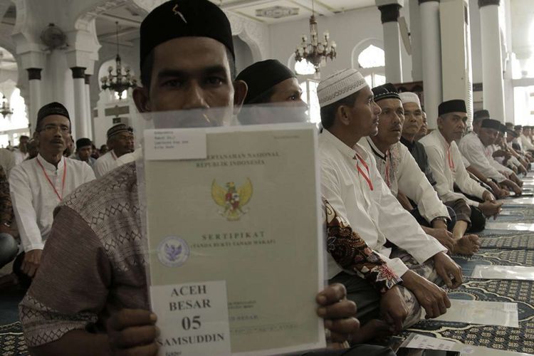 Warga menunjukkan sertifikat tanah wakaf yang diserahkan Presiden Jokowi secara simbolis untuk masjid, menasah, dan pesantren yang ada di Provinsi Aceh, Jumat (14/12/2018).