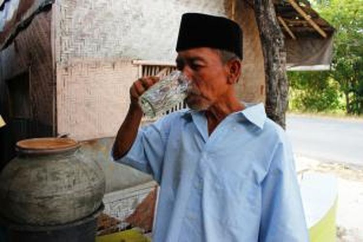 Wahadi (55), bersama istri dan cucu, sedang beristirahat dan meminum air dari Gentong Haji di Desa Kejuden, Blok Karang Turi, Kecamatan Depok, Kabupaten Cirebon, Senin (22/9/2014). Selain menghilangkan haus, ia berharap mendapat berkah agar diberi kemudahan pergi ibadah haji kelak.