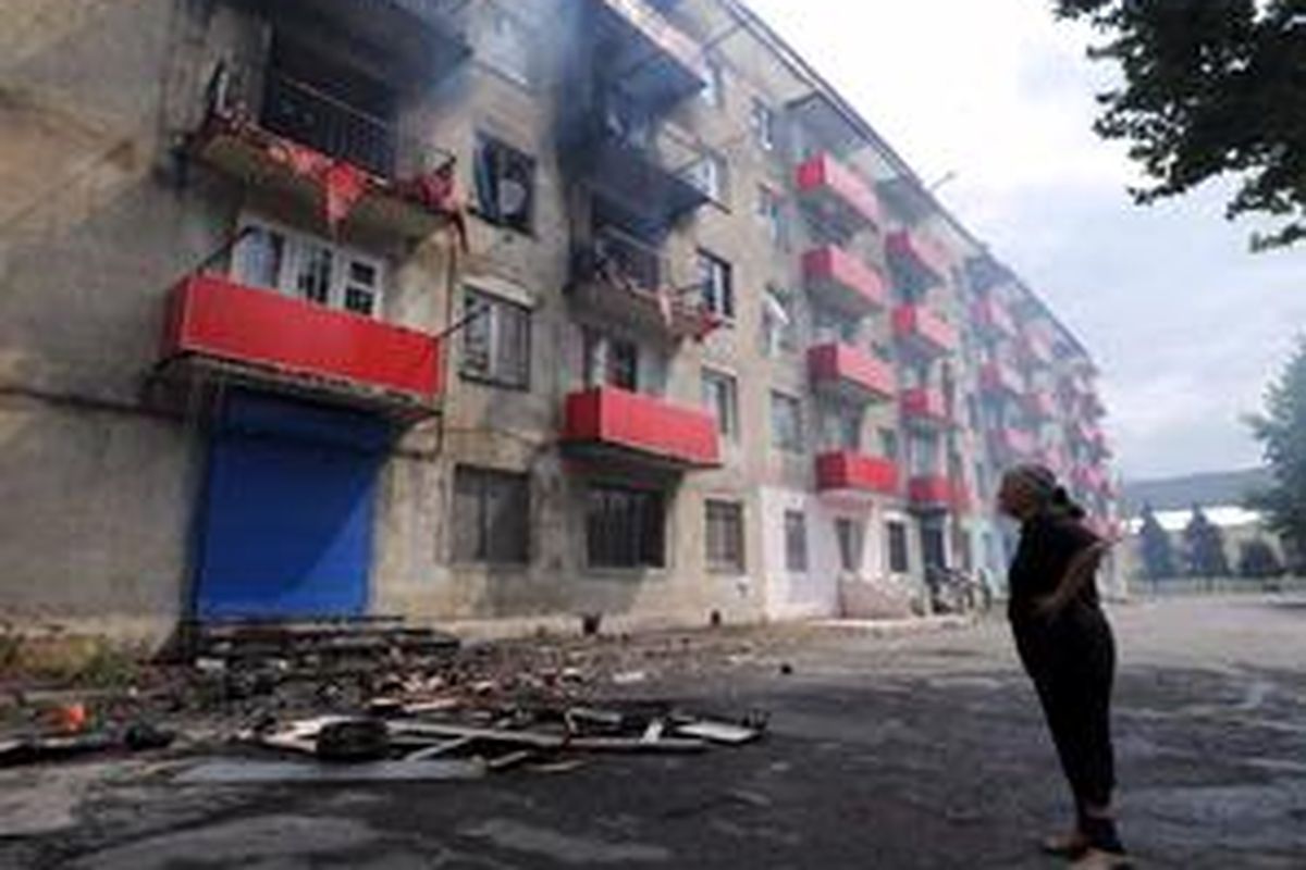 Seorang perempuan mengamati rumahnya di Gori Georgia yang hangus akibat serangan mortir Rusia, Selasa (12/8).