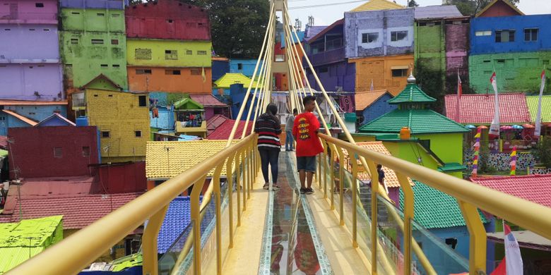 Sejumlah wisatawan saat melintas di jembatan kaca yang menghubungkan Kampung Warna - warni dan Kampung Tridi di Kota Malang, Jawa Timur, Selasa (10/10/2017)