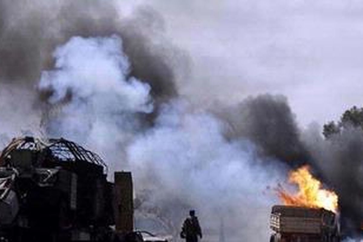 Seorang personel pemberontak menyaksikan beberapa kendaraan milik rezim Khadafy yang digulung dengan kobaran api setelah pasukan koalisi melancarkan serangan udara di Benghazi