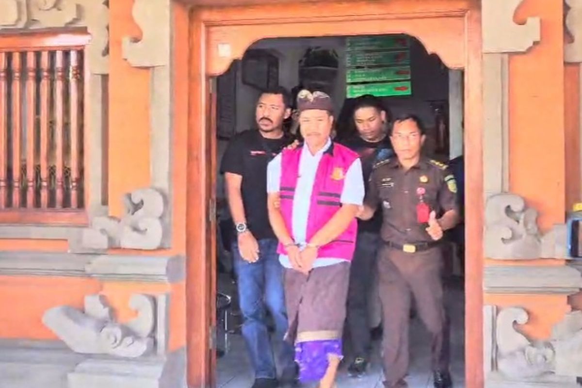 Kepala Dinas PMPTSP Kabupaten Buleleng, IMK digiring ke mobil tahanan kejaksaan dengan tangan diborgol usai ditetapkan sebagai tersangka, Kamis (20/3/2025).