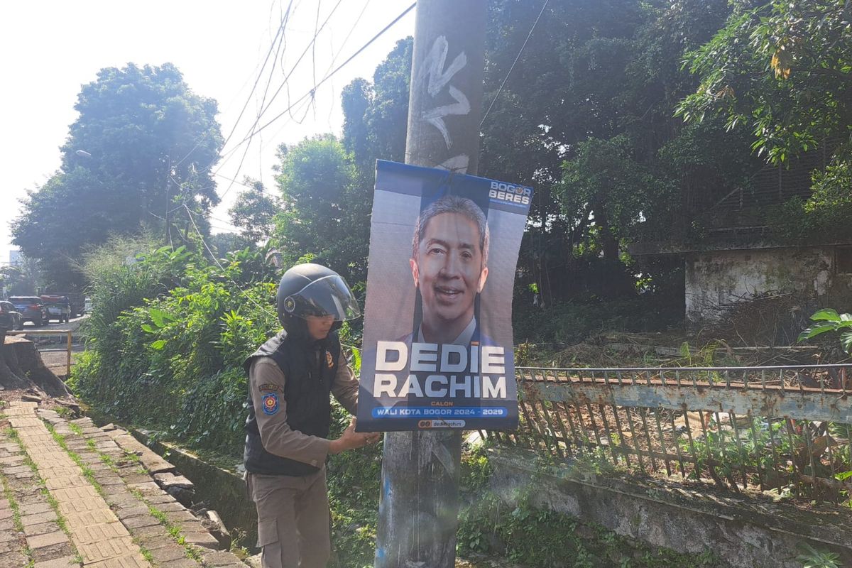 Seorang anggota Satpol PP Kota Bogor sedang mencopot salah satu spanduk bakal calon wali kota (bacawalkot) karena dinilai melanggar aturan, Selasa (28/5/2024).