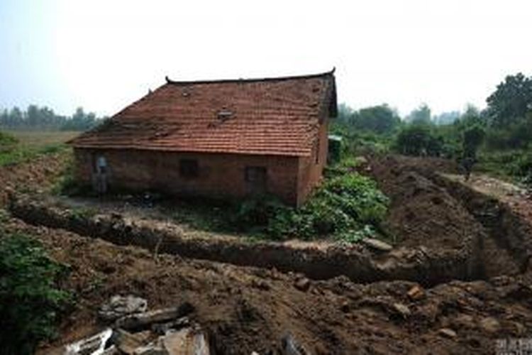 Pengembang menggali tanah di sekeliling rumah petani tua.