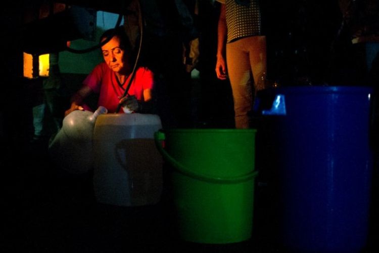 Orang-orang mengantre untuk air minum yang didistribusikan di Chacao, Caracas, Venezuela, Senin (11/3/2019). (AFP/CRISTIAN HERNANDEZ)