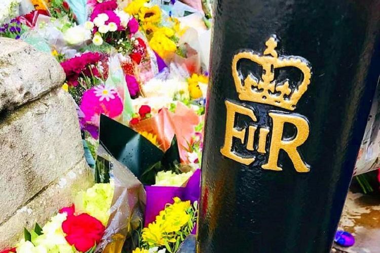 Karangan bunga belasungkawa di samping sandi tahta kerajaan Ratu Elizabeth II berkode EIIR membanjiri luar pagar kediaman resmi Monarki Inggris Istana Buckingham di jantung kota London di distrik Westminster Jumat (9/9/2022). 