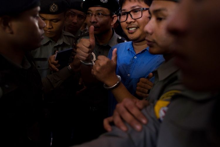 Jurnalis Reuters, Wa Lone (tengah) dijaga polisi ketika tiba di pengadilan di Yangon, Myanmar, Rabu (10/1/2018). (AFP/Ye Aung Thu)