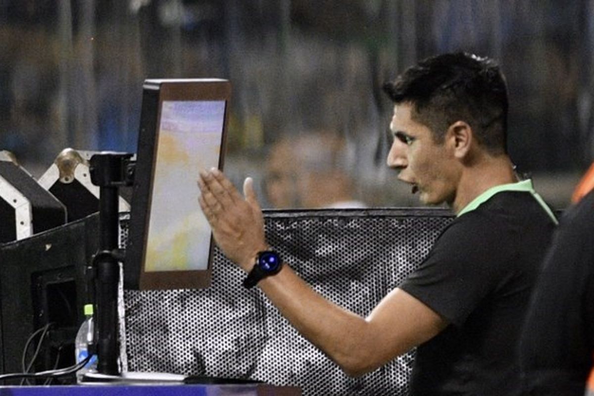 Wasit Luis Quiroz mengecek tayangan VAR (Video Assistant Referee) dalam laga fase grup Copa Sudamericane antara Blooming vs Santos di Stadion Ramon Aguilera Costas pada 4 April 2023. Terkini, PSSI tengah berupaya untuk menggunakan VAR di Indonesia. Direktur Utama PT LIB, Ferry Paulus, penggunaan VAR memakan biaya Rp 100 miliar. (Foto oleh AIZAR RALDES / AFP)
