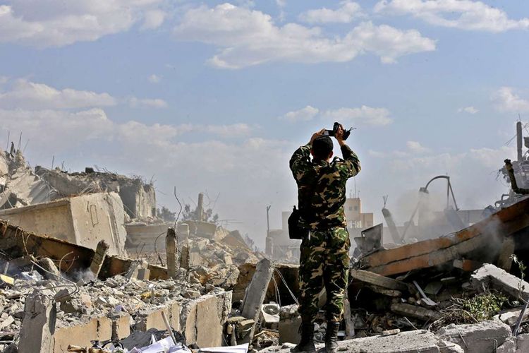 Tentara Suriah memeriksa puing-puing bangunan, bagian dari kompleks Pusat Penelitian dan Penelitian Ilmiah di distrik Barzeh, utara Damaskus, saat tur media yang diselenggarakan Kementerian Informasi Suriah, Sabtu (14/4/2018). Amerika Serikat dan sekutunya, Perancis dan Inggris, melancarkan serangan ke Suriah sebagai respons terhadap dugaan serangan senjata kimia yang dilakukan Suriah di kota Douma pada 7 April lalu.