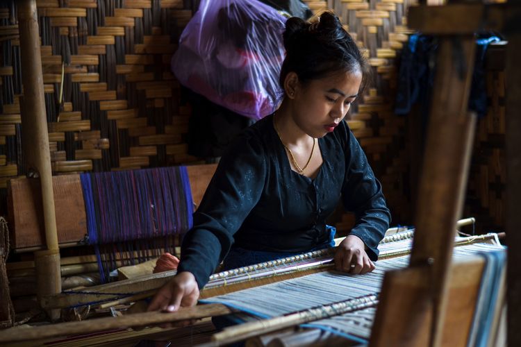 Potret penenun di Baduy Luar sedang menenun kain. 