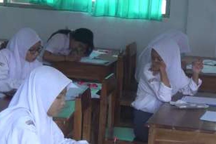 Salah seorang peserta Ujian Nasional (UN) di salah satu Sekolah Menengah Atas (SMA) Negeri di Sungguminasa, Kabupaten Gowa, Sulawesi Selatan mencontek dan bekerjasama dengan peserta UN lainnya. Senin, (04/04/2016).