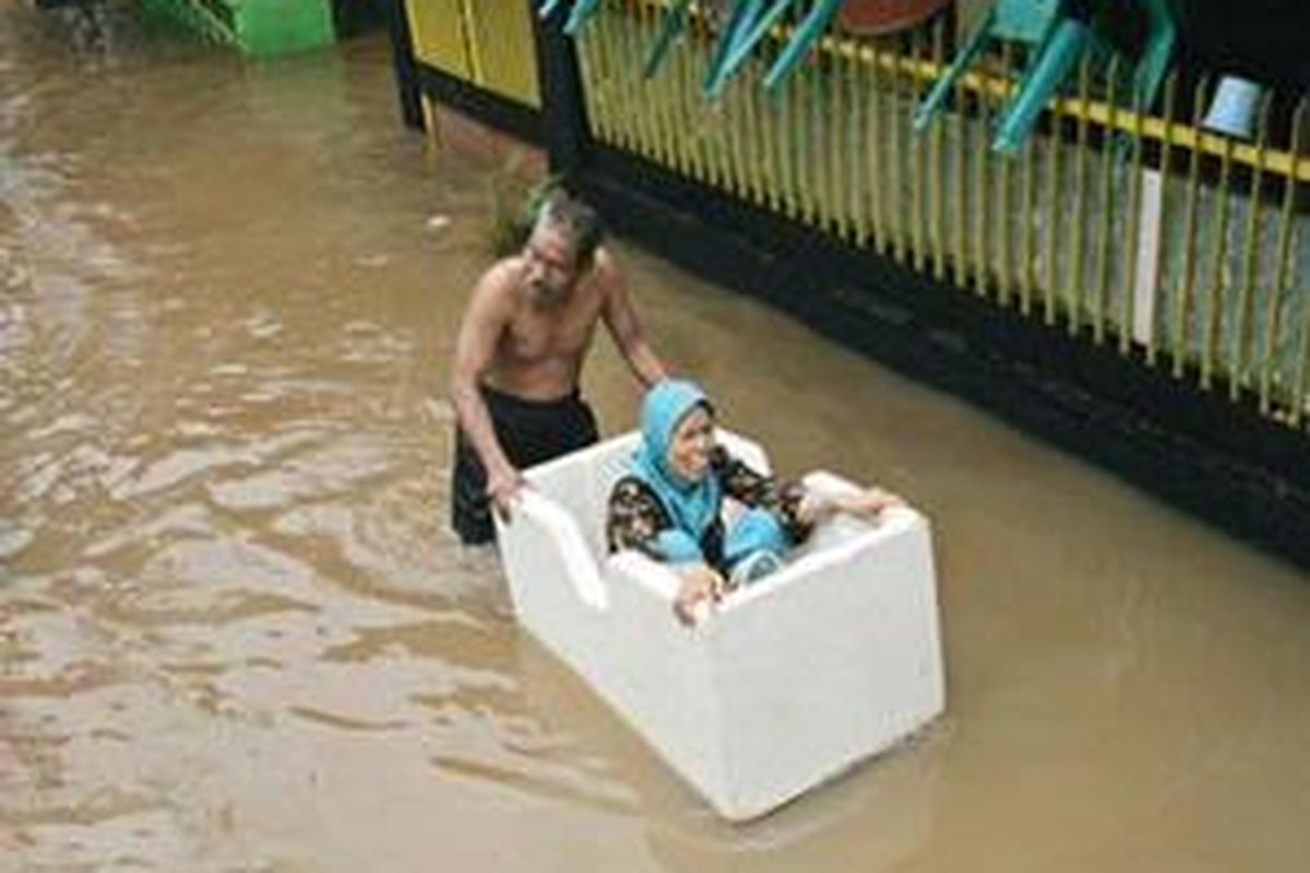 Dua warga Kampungpulo, Kampungmelayu, Jakarta Timur, mengungsi dari rumahnya yang tergenang banjir setinggi sekitar setengah meter, Senin (3/11). Dalam beberapa hari ke depan, kawasan ini bisa dilanda banjir besar.