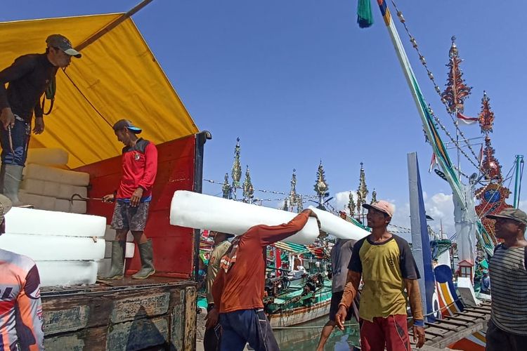 Buruh angkut di Pelabuhan Muncar Banyuwangi membawa balok ke ke kapal yang akan berlayar mencari ikan pada Selasa (14/3/2023)