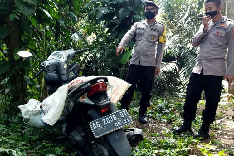 Polisi menunjuk karung pakan ternak di atas sepeda motor yang berisi mayat perempuan di area kebun sengon di Desa Kawedusan, Kecamatan Ponggok, Kabupaten Blitar, Rabu (1/9/2021)