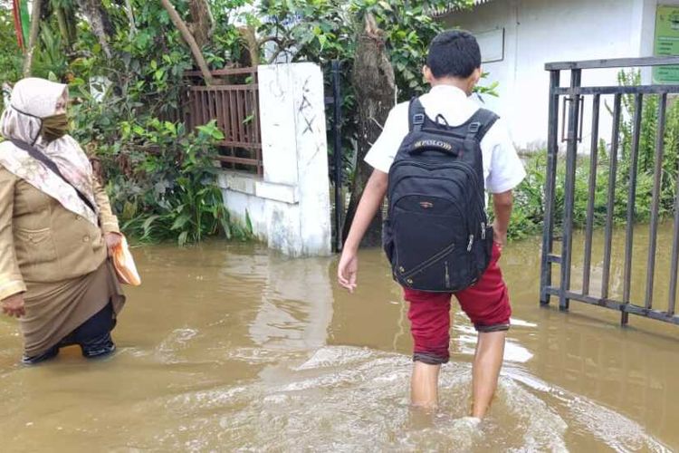Seorang siswa SDN 140 Pekanbaru menerjang banjir menuju sekolahnya untuk mengikuti gladibersih ANBK, di Jalan Karya Bersama, Kelurahan Bambu Kuning, Kecamatan Tenayan Raya, Kota Pekanbaru, Riau, Senin (25/10/2021).