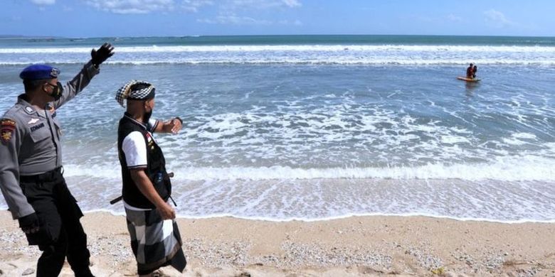 Polisi bersama Pecalang atau petugas keamanan adat Bali meminta wisatawan untuk meninggalkan kawasan wisata Pantai Kuta di Badung, Bali, Sabtu (03/07).