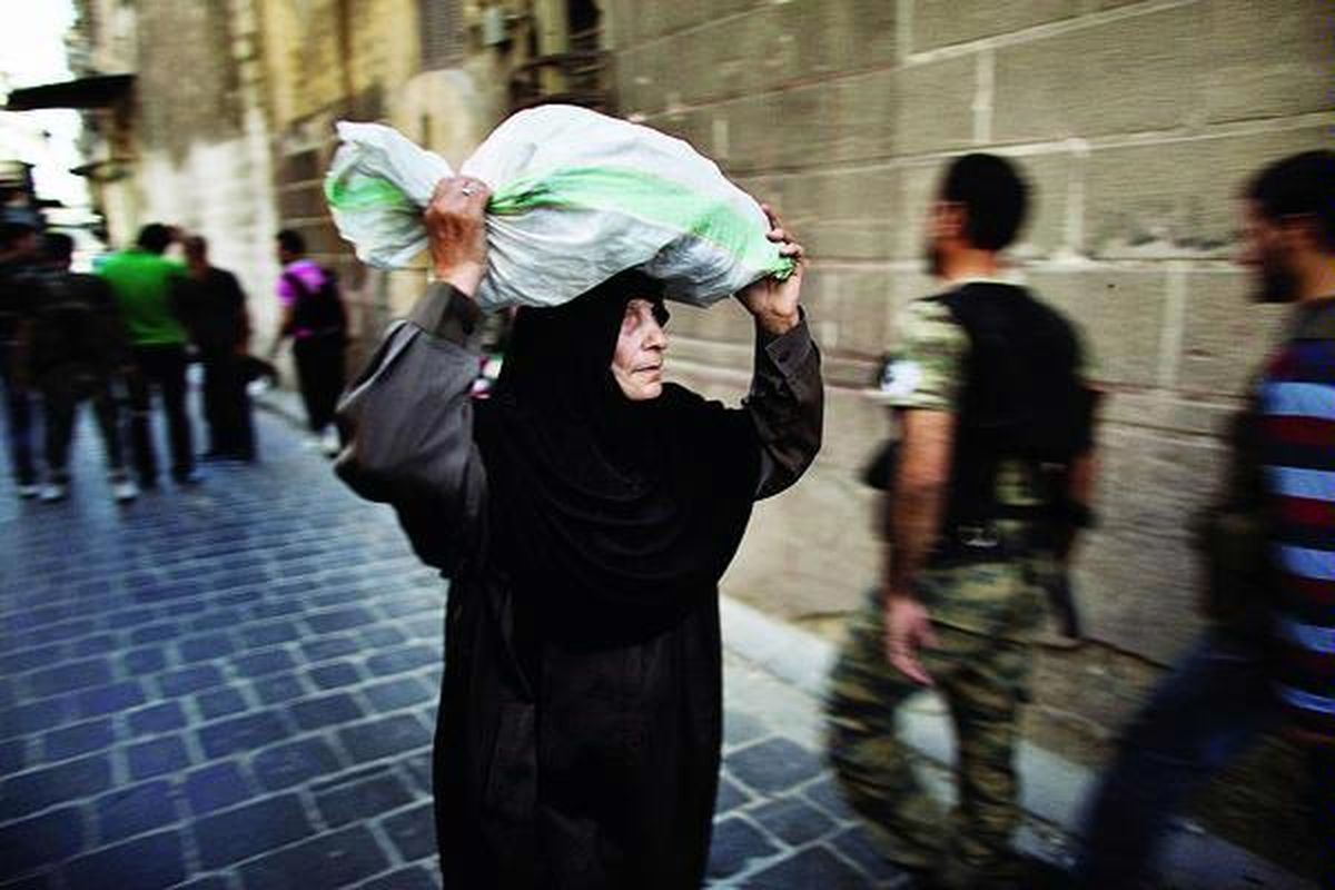 Warga Suriah, yang sedang membawa karung berisi makanan, berpapasan dengan pasukan oposisi Tentara Pembebasan Suriah (FSA) di kawasan Kota Tua di Aleppo, Suriah, Minggu (16/9). Lebih dari 20.000 orang tewas sejak konflik terjadi di Suriah, Maret 2011.