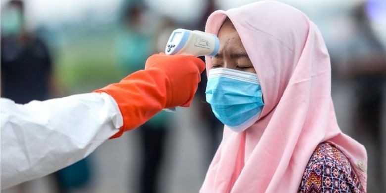 Seorang pekerja migran Indonesia diperiksa suhu tubuhnya saat tiba di Lanud Soewondo di Medan, Sumatera Utara, 10 April 2020 lalu.