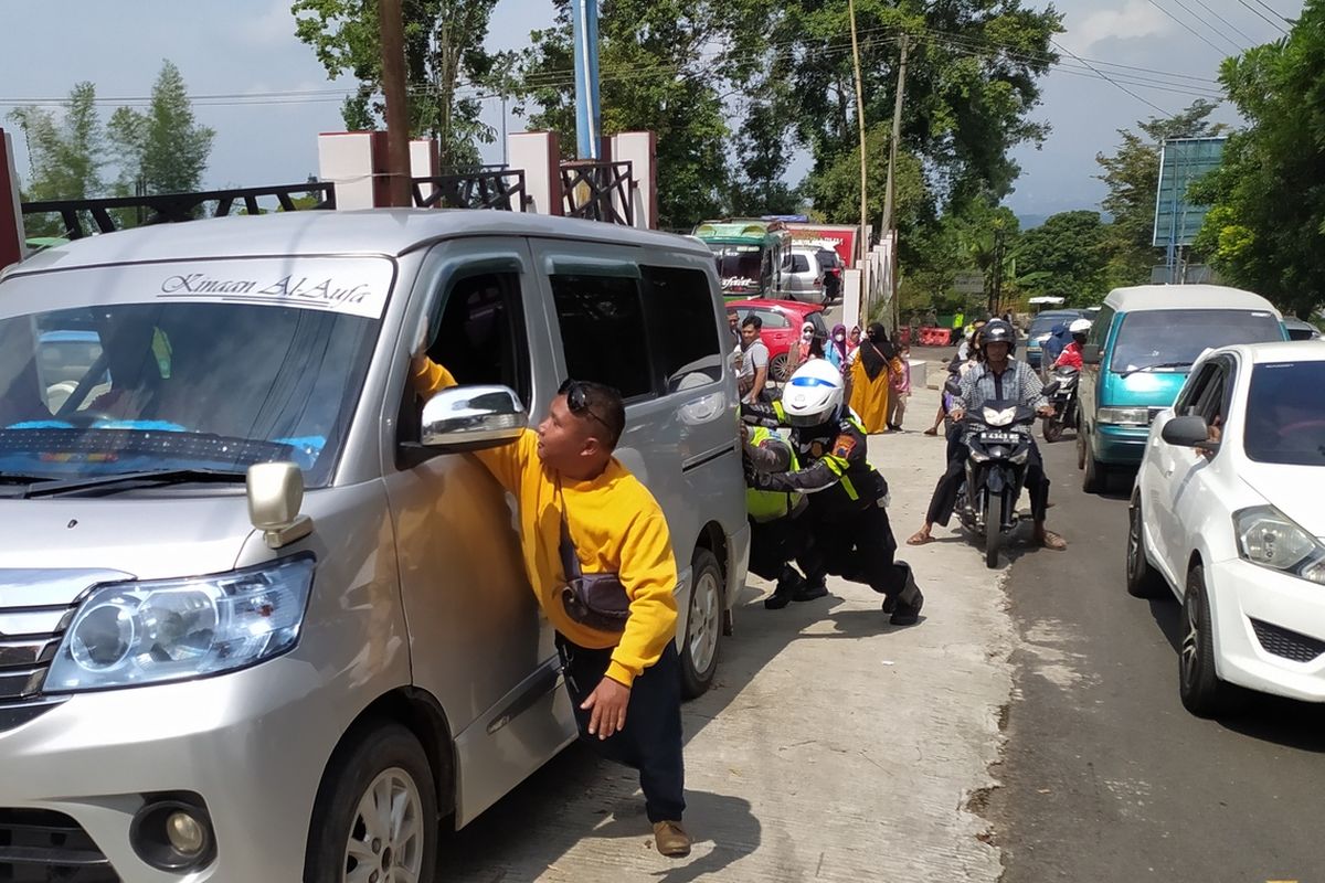 Polisi dan warga mendorong mobil yang mogok di jalur wisatawan Baturraden, Kabupaten Banyumas, Jawa Tengah, Kamis (5/5/2022).