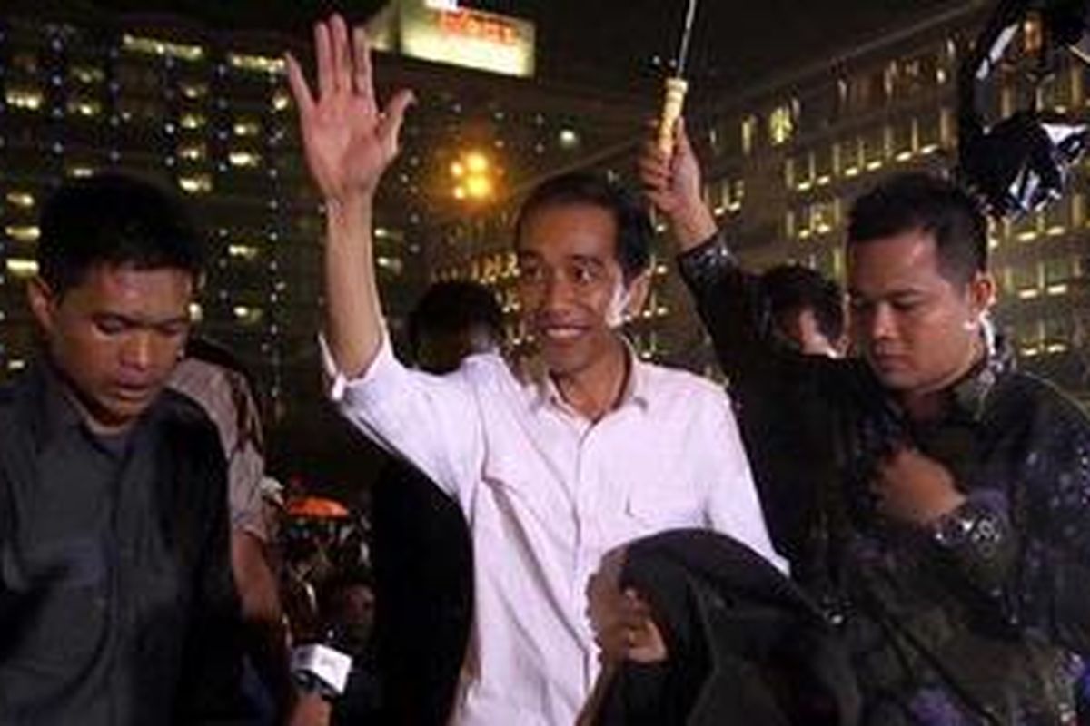 Hujan mengguyur Jakarta saat perayaan malam tahun baru 2013 di Bundaran HI, Jakarta Pusat. Gubernur DKI Jakarta Joko Widodo yang hadir pada acara tersebut sampai dipayungi ajudannya.