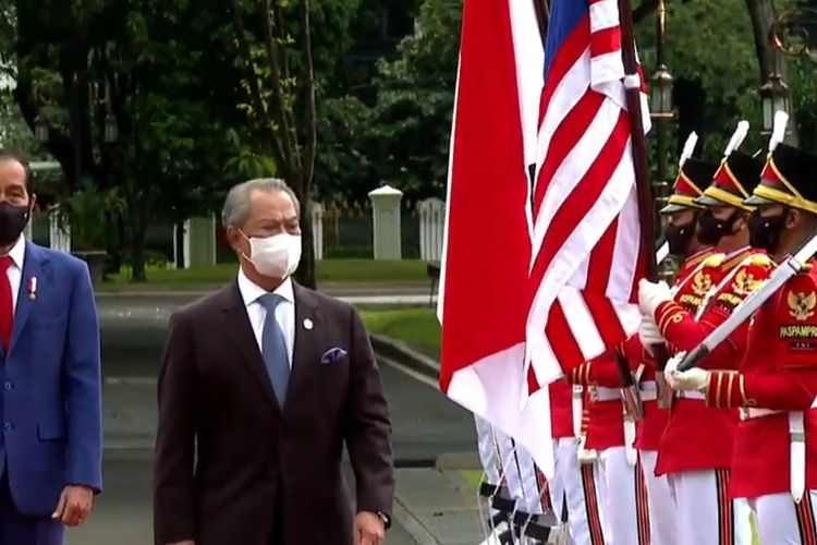 Screen grab of Malaysia's Prime Minister Muhyiddin Yassin (right) inspecting the guard of honor at Merdeka Palace in Jakarta during his state visit to Indonesia on Friday February 5, 2021. Accompanying him is Indonesia's President Joko Widodo (left).  