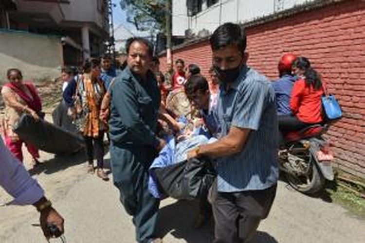 Beberapa orang staf sebuah rumah sakit di Kathmandu, Nepal menggotong seorang pasien keluar dari bangunan rumah sakit saat gempa berkekuaTAN 7,4 skala Richter kembali mengguncang negeri itu pada Selasa (12/5/2015).