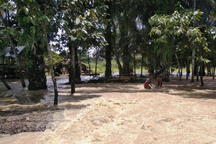 Dua anak melintas di jalan yang terendam banjir di Desa Nga, Kecamatan Lhoksukon, Kabupaten Aceh Utara, Rabu (26/9/2018).