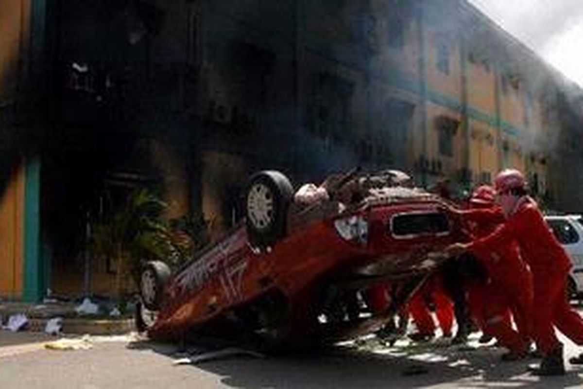 Para pekerja membalik mobil yang dirusak massa dari buruh galangan kapal PT Drydocks World Graha di Tanjung Uncang, Batam, Kamis (22/4/2010).
