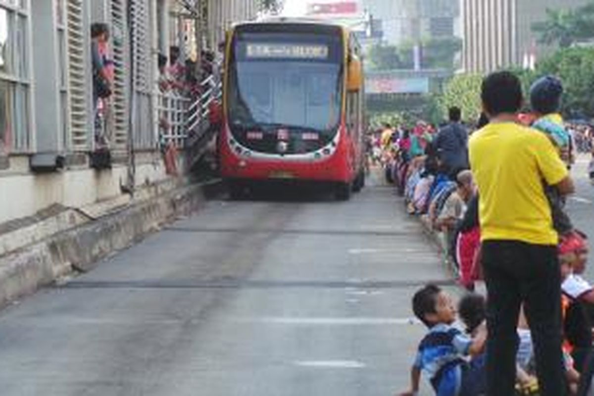 Pemandangan pengunjung Jakarnaval yang duduk di sepanjang sparator buswat Koridor I, di kawasan Jalan MH Thamrin, Jakarta Pusat. Minggu (22/6/2014). Transjakrta tetap beroperasi di acara Jakarnaval ini. 