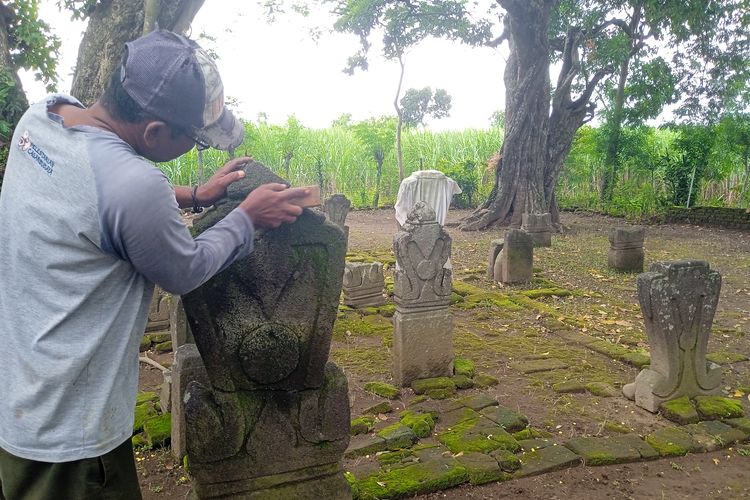 Juru Pelihara Situs Nduro, Sugeng (47), saat membersihkan lumut yang menempel di nisan pada kompleks pemakaman kuno Dusun Nanggungan, Desa Watudandang, Kecamatan Prambon, Kabupaten Nganjuk, Jawa Timur, Rabu (13/3/2024)