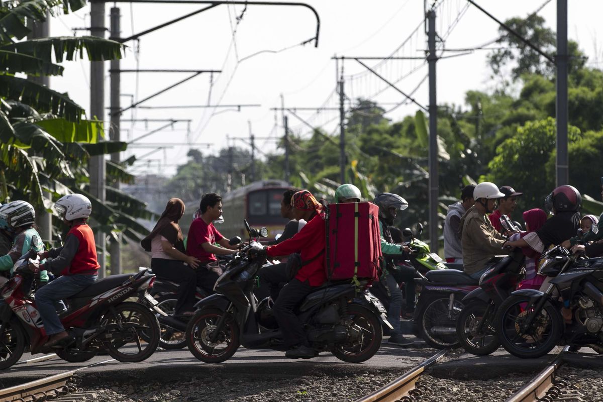 Pengguna jalan melintas di perlintasan kereta api di wilayah Bumi Bintaro Permai, Pondok Aren, Jakarta Selatan, Minggu (23/2/2020). Tidak berfungsinya palang pintu di perlintasan kereta api sejak 2 tahun lalu mengancam keselamatan warga.