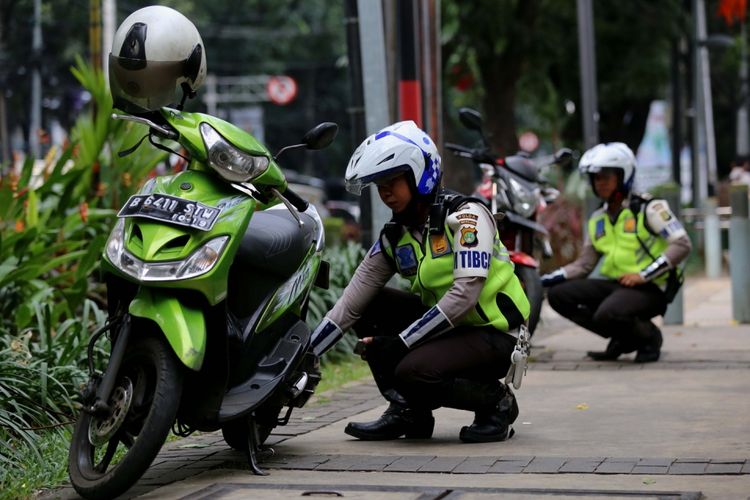 Polisi menggembosi ban sepeda motor yang parkir sembarangan di Jalan Kebon Sirih, Jakarta Pusat, Senin (17/7/2017). Pengendara sering memanfaatkan trotoar untuk memotong jalan agar bisa lebih cepat ketimbang melewati jalan raya.