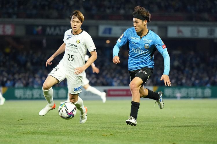 Dua pemain dari klub berbeda J League tengah beraksi di atas lapangan permainan.