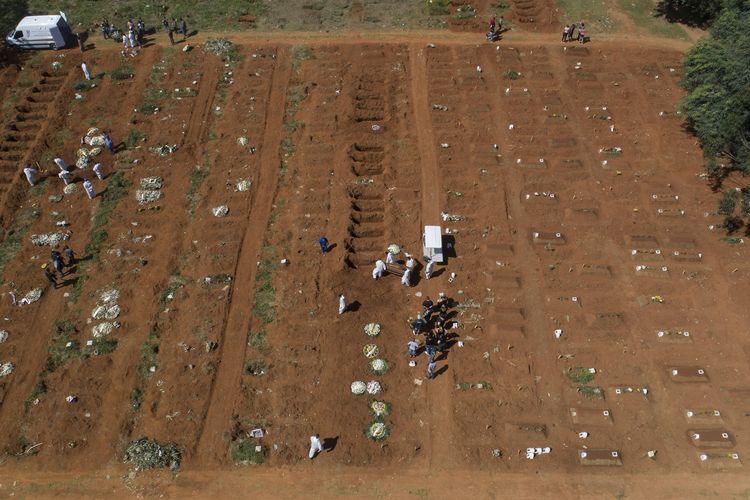 Petugas pemakaman mengenakan pakaian pelindung lengkap bekerja menurunkan jenazah korban meninggal Covid-19 di Pemakaman Vila Formosa, Sao Paulo, Brasil, pada 24 Maret 2021.