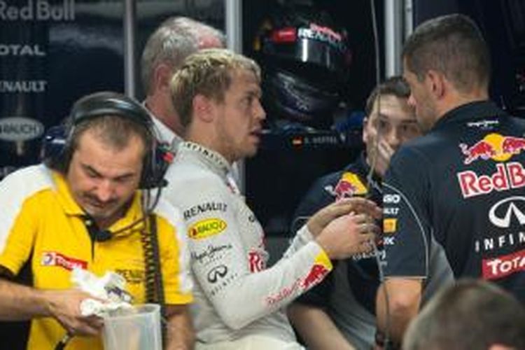 Pebalap Red Bull Racing asa Jerman, Sebastian Vettel (tengah) berdiskuisi dengan timnya saat menjalani sesi latihan bebas dua GP India di Sirkuit Buddh International, Jumat (25/10/2013).