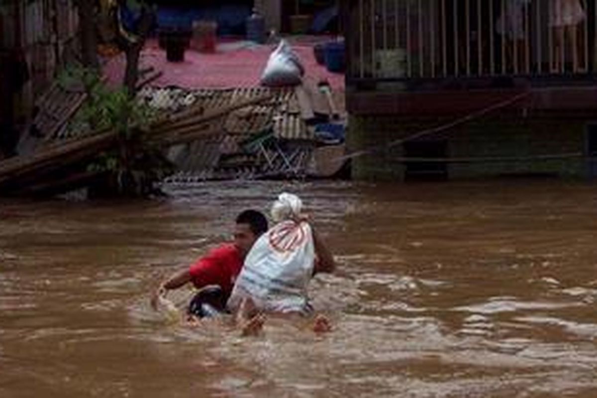 Warga membawa barang dari Pasar Bukit Duri Tanjakan menyeberangi Kali Ciliwung dari Bukit Duri, Tebet Jakarta Selatan menuju Kampung Pulo, Kampung Melayu, Jatinegara, Jakarta Timur, Selasa (5/3/2013). Ketinggian air banjir bervariasi dari 30 sentimeter hingga 2,5 meter. Banjir yang mulai pukul 02.30 WIB tersebut merendam ratusan rumah di bantaran Kali Ciliwung.
