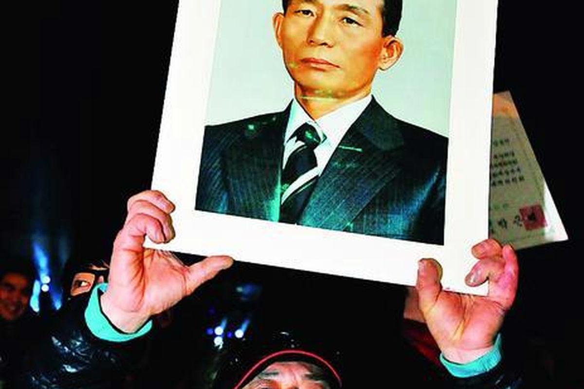 Pendukung presiden terpilih Korea Selatan, Park Geun-hye, mengacungkan foto ayah Geun-hye, mantan presiden dan diktator militer, Park Chung-hee, setelah pidato kemenangan Geun-hye di Seoul, Kamis (20/12).